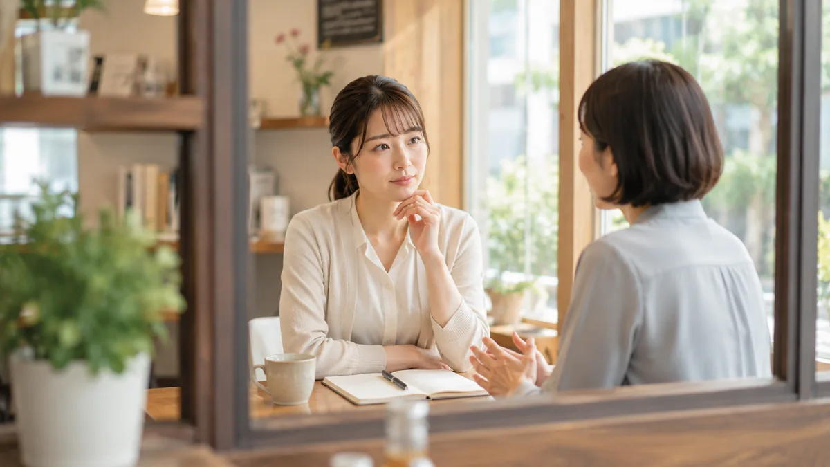 仕事を取られる状況が続く職場で、このまま働くか環境を変えるか第三者に相談しながら今後の働き方について考えている女性 