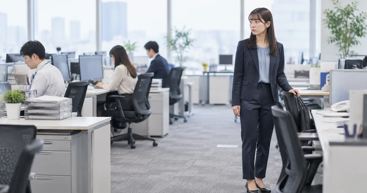 仕事をする同僚を少し離れた位置から気にする女性